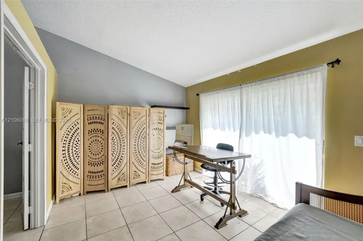 Room featuring a vaulted ceiling, neutral tile flooring, and large sliding glass doors