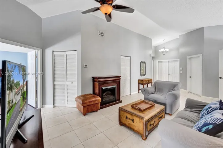Living area featuring vaulted ceilings, tile flooring, a fireplace, and a ceiling fan