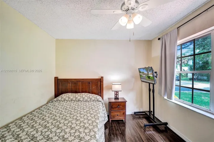 Room featuring wood-finish flooring, a multi-light ceiling fan, and a grid-pane window