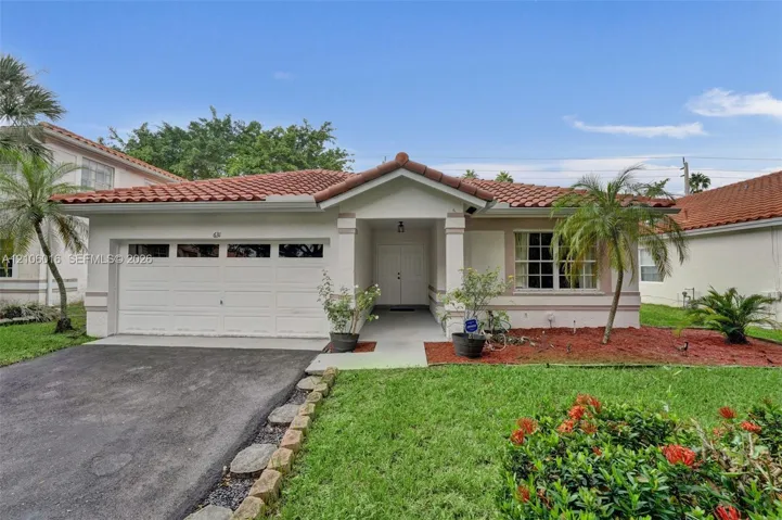 Stucco exterior featuring a tiled roof, covered entryway, multi-panel garage door, and defined landscape beds