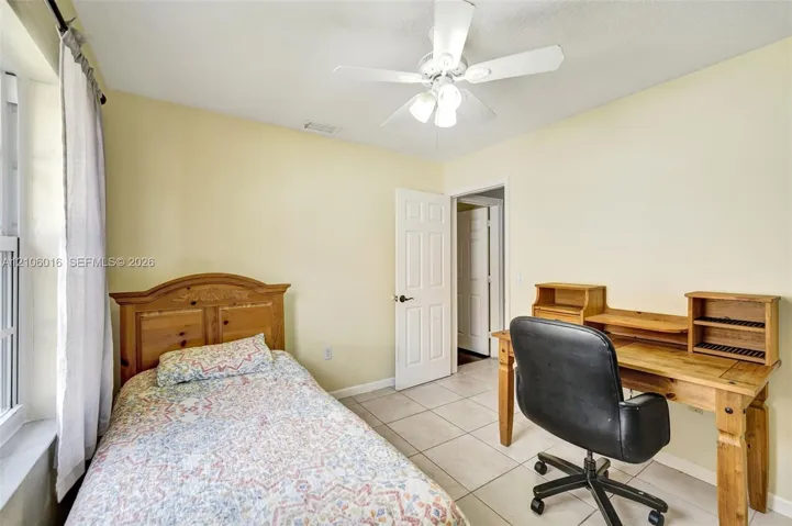 Neutral-toned interior featuring tile flooring, a multi-blade ceiling fan with integrated lighting, and a six-panel interior door