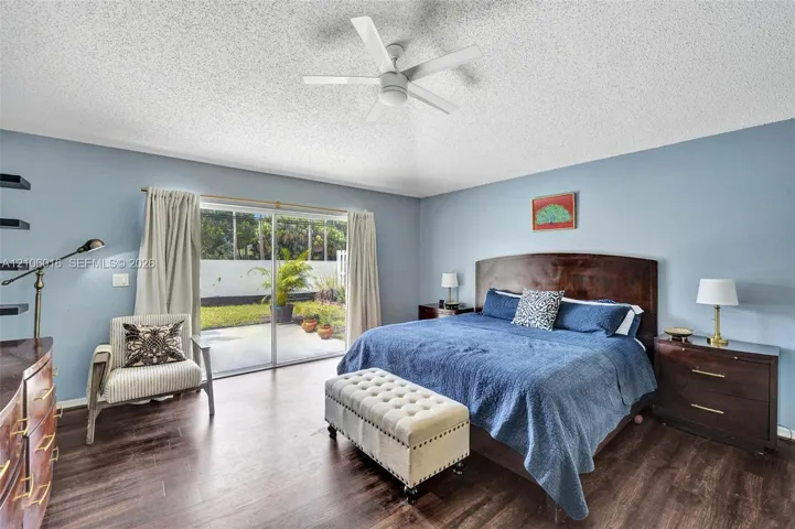 Spacious room featuring wood-finish flooring, a ceiling fan, and sliding glass doors providing outdoor access