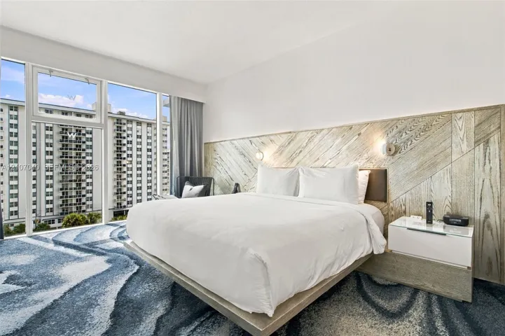 Floor-to-ceiling windows, custom wood-paneled accent wall, built-in platform bed frame, and wall-mounted reading lights
