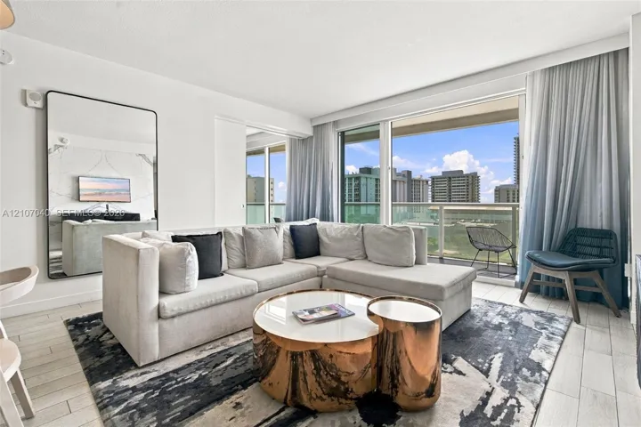 Living area featuring floor-to-ceiling glass sliding doors, private balcony, large format tile flooring, and a stone-clad accent wall