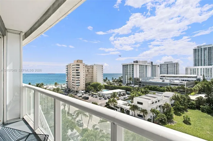 Covered balcony featuring a glass-panel railing and open ocean horizon