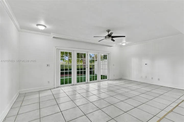 Interior space featuring large-format tile flooring, crown molding, multi-panel glass patio doors, and a ceiling fan