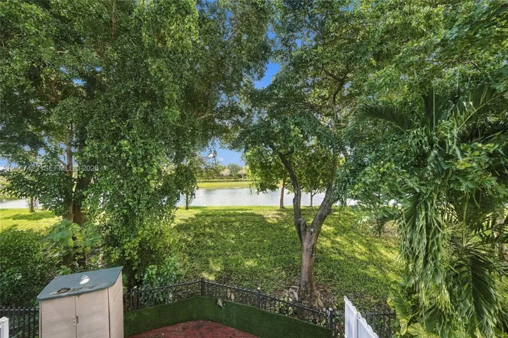 Backyard featuring mature trees, a water feature, ground-level hardscaping, and decorative perimeter fencing
