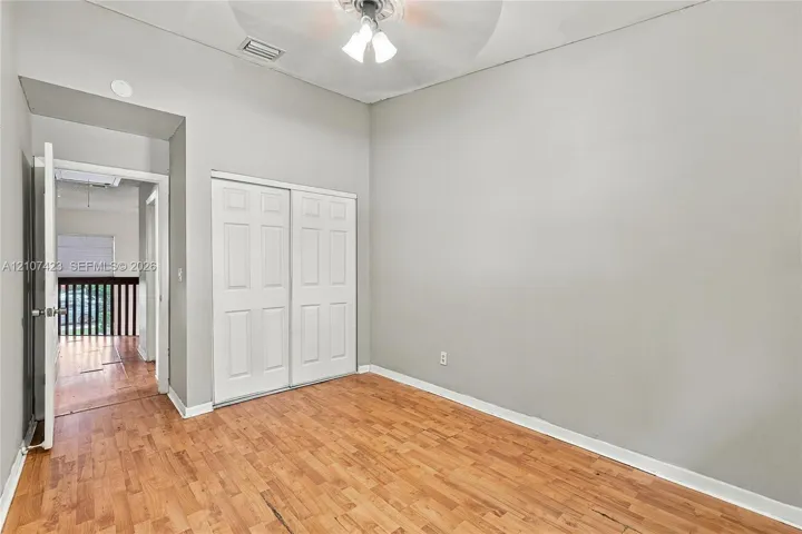Room featuring wood-finish flooring, high ceilings, ceiling-mounted light fixture, and double-door closet