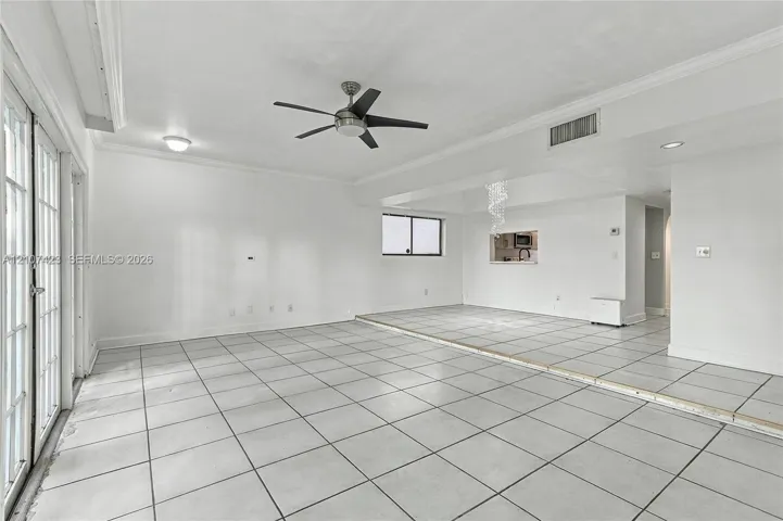 Interior space featuring large-format ceramic floor tile, crown molding, a multi-blade ceiling fan with integrated lighting, recessed lighting, and a multi-pane glass door system