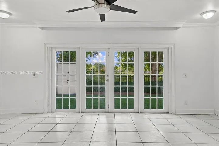 Set of four glass-paned French doors, neutral tile flooring, recessed and flush-mount ceiling lighting, and a multi-blade ceiling fan with integrated light