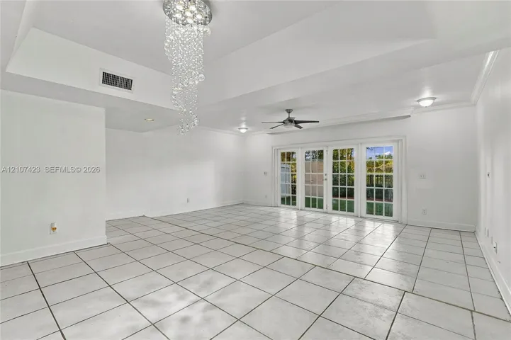 Tray ceiling with recessed lighting, crystal-style chandelier, ceramic tile flooring, and multi-panel French doors