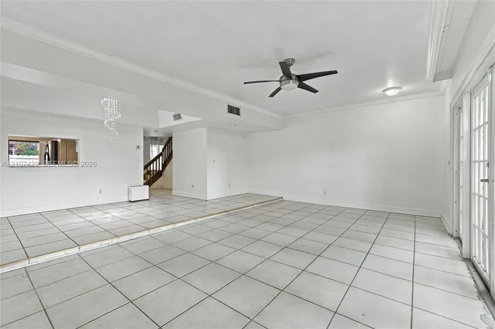 Sunken living area featuring large-format tile flooring, a tiered floor plan, a ceiling fan, and multi-pane glass doors