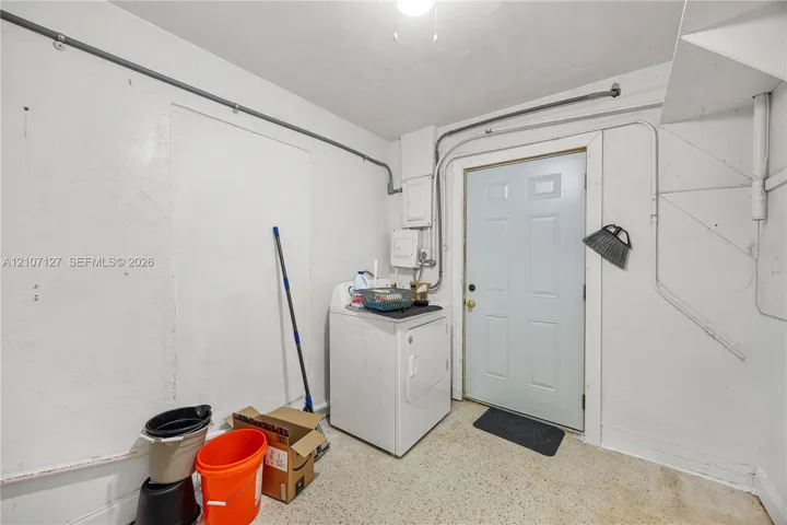 Utility space featuring smooth wall finishes, overhead lighting, and a six-panel exterior access door
