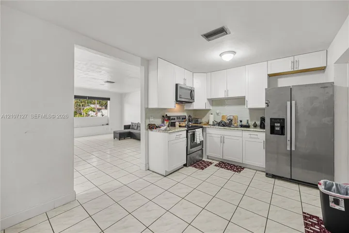 Kitchen featuring white cabinetry, stone-finish countertops, stainless steel appliances, and tiled flooring