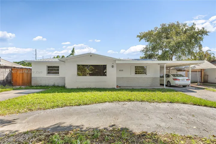 Single-story residence featuring a smooth stucco exterior, a wide front window, a concrete driveway, and an attached carport