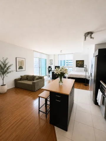 Open-concept interior featuring wood-finish flooring, tile kitchen flooring, a central island with a wood countertop, large-pane glass balcony doors, and track lighting