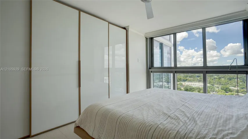 Floor-to-ceiling windows, built-in floor-to-ceiling closets with white panels and trim, and a ceiling fan