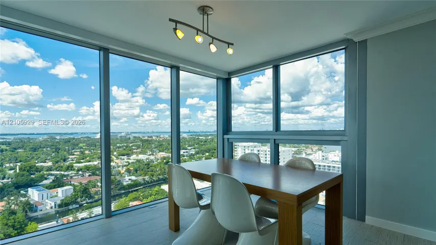 Floor-to-ceiling windows, panoramic exterior scenery, modern four-light ceiling fixture, and wood-finish flooring