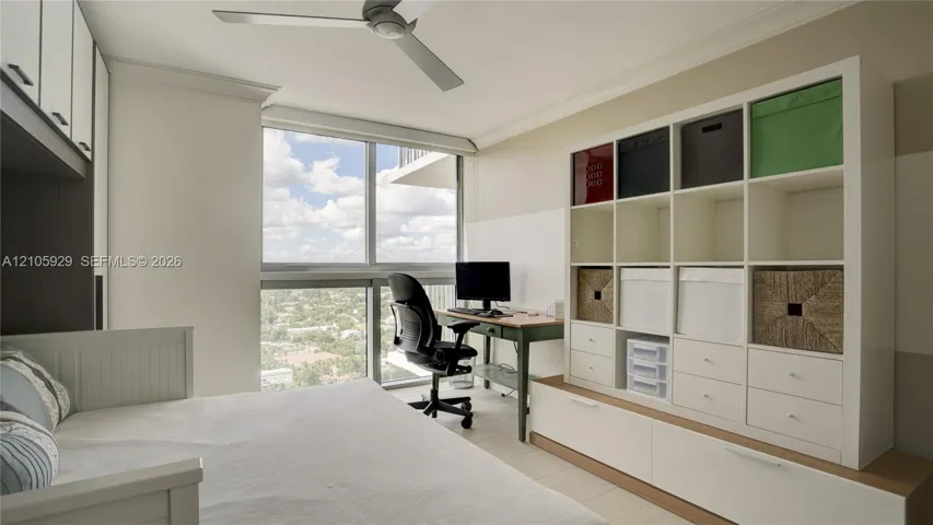 Floor-to-ceiling windows, built-in floor-to-ceiling white cabinetry, and a ceiling-mounted fan