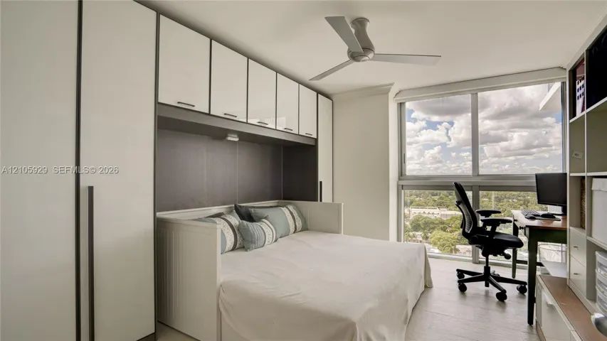 Floor-to-ceiling windows, built-in white cabinetry, integrated recessed lighting, and a modern ceiling fan
