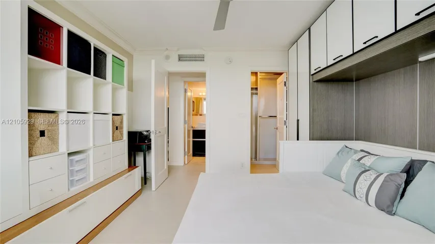 Room featuring extensive built-in white shelving, custom cabinetry with integrated overhead storage, ceiling-mounted fan, and tile flooring