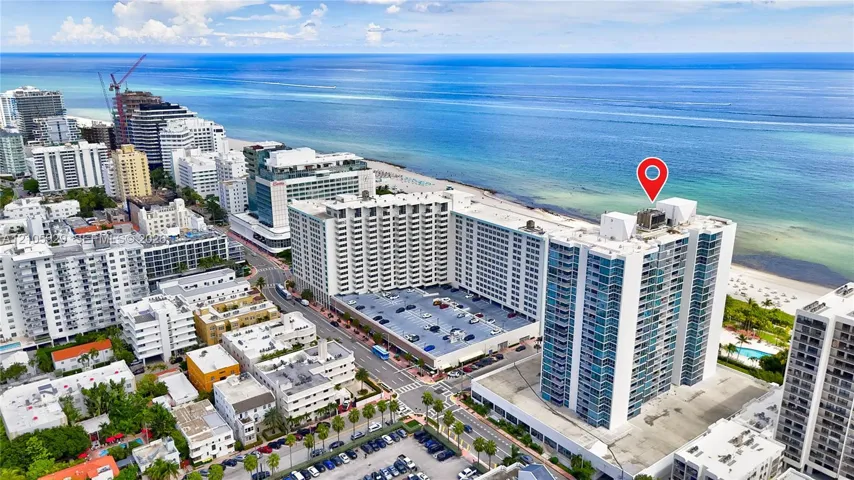 Aerial perspective of a high-rise residential building featuring expansive glass facade elements and proximity to the coastline