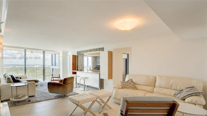 Open-concept interior featuring light-toned flooring, floor-to-ceiling glass sliding doors, and a kitchen area with a built-in counter
