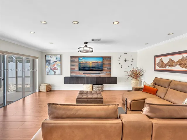 Open-concept living space featuring wood-finish flooring, recessed lighting, a floating media console, and a reclaimed wood-style accent wall
