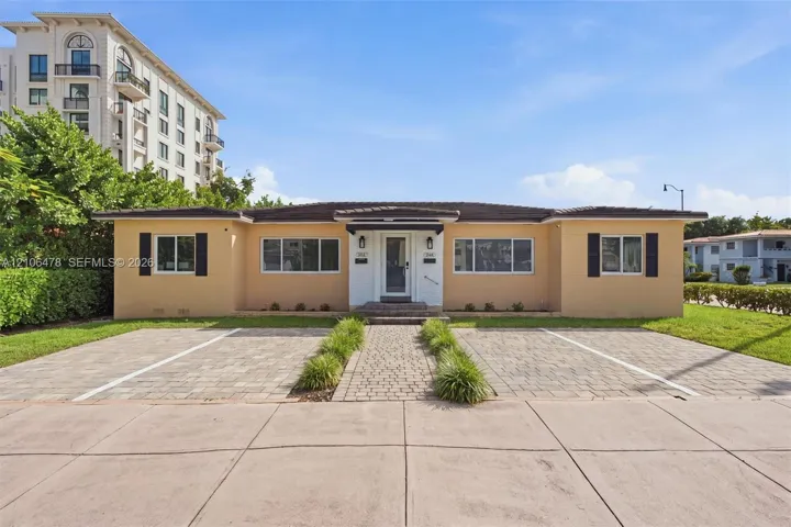 Single-story exterior featuring a central entryway, dual paver parking pads, a decorative paver walkway, and dark shutter accents