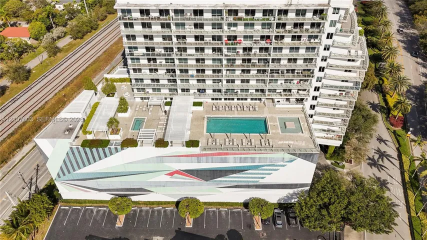 Multi-story residential building featuring a sprawling elevated terrace with a swimming pool, multiple pergola structures, concrete hardscaping, and decorative mural exterior facade