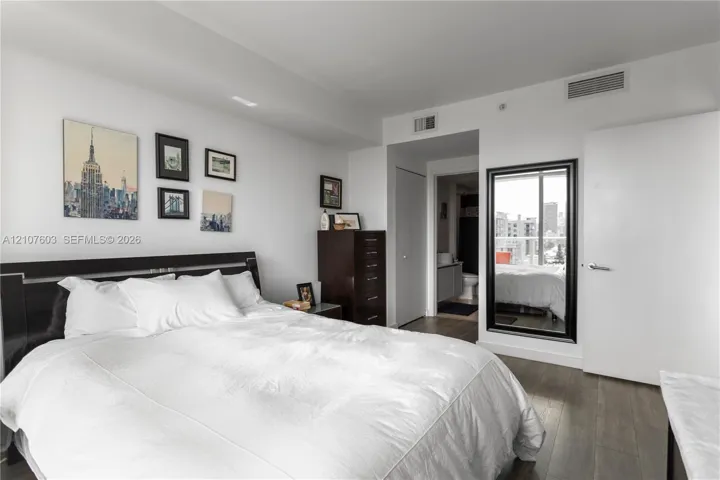 Wood-finish flooring, full-length wall mirror with a black frame, and ceiling-integrated climate control system