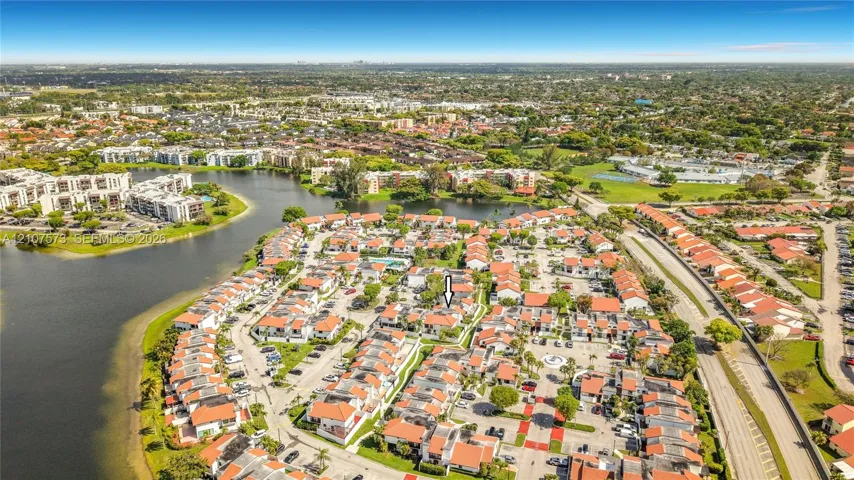 Aerial perspective of residential community featuring multi-unit structures with terracotta-style roofs and mature landscaping