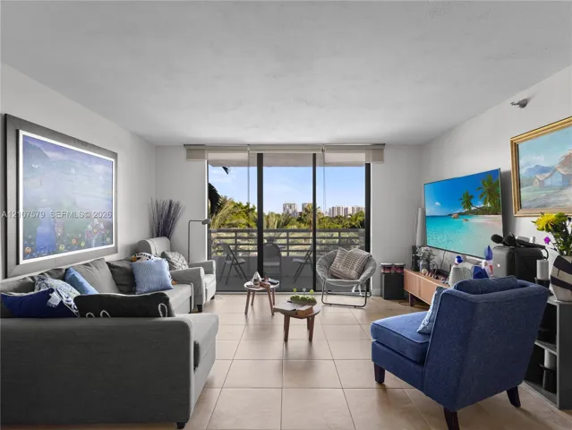 Living area featuring neutral ceramic tile flooring and floor-to-ceiling sliding glass doors opening to a private balcony