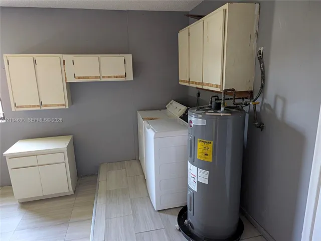 Utility space featuring light-toned cabinetry, neutral wall-finish, and tile flooring