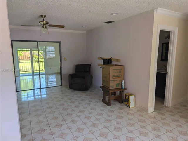 Living area featuring patterned tile flooring, recessed lighting, a ceiling fan, and a glass sliding door