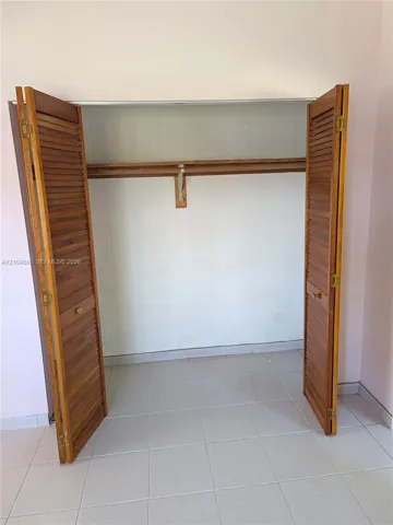 Storage space featuring bi-fold wooden louvered doors and a built-in shelf