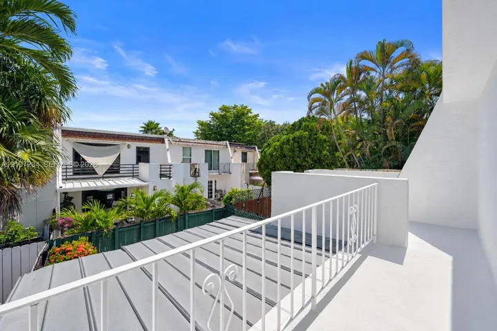 Elevated balcony featuring a white metal railing, solid flooring, and a metal-paneled roof covering