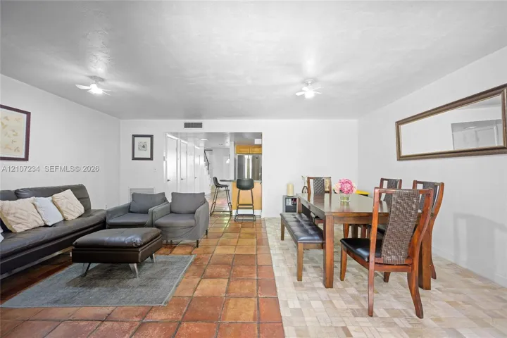 Open-concept floor plan featuring large-format terra cotta tile flooring, dual ceiling-mounted light fixtures, and a wall-mounted rectangular mirror