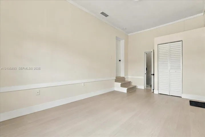 Interior space featuring wood-finish flooring, chair rail molding, louvered closet doors, and multi-level floor elevation