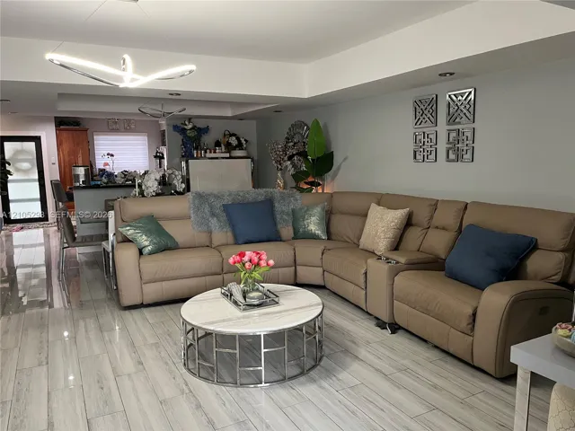 Open-concept interior featuring wood-finish tile flooring, recessed ceiling lighting, a modern geometric pendant light fixture, and crown molding