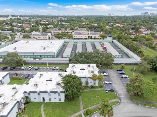 Aerial view of commercial property featuring paved parking areas, multi-unit flat-roof structures, and maintained landscape surroundings