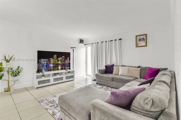 Living area featuring neutral tile flooring, crown molding, and a sliding glass door