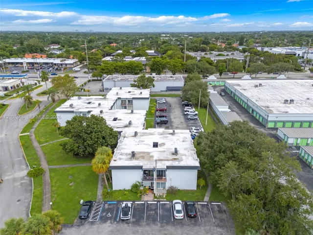 Multi-level building exterior featuring a flat roofline, painted masonry facade, assigned asphalt parking, and landscaped grounds with mature trees