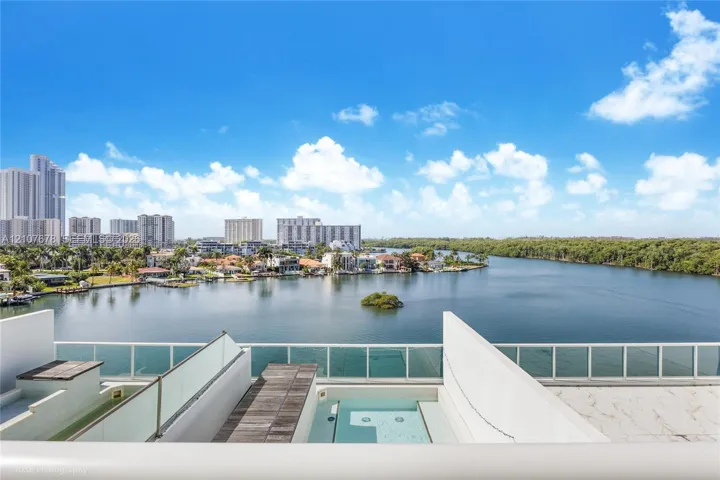 Private terrace featuring a built-in plunge pool, wood-finish decking, and tempered glass railings overlooking the waterfront