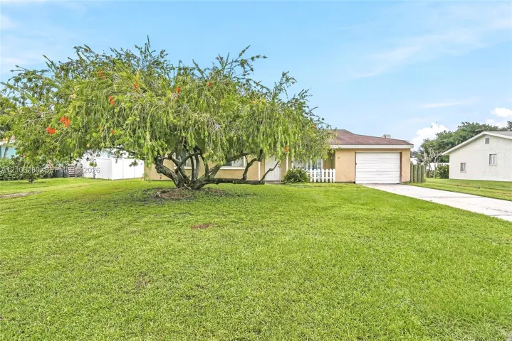 Single-story exterior featuring a stucco facade, attached one-car garage, concrete driveway, and mature landscaping