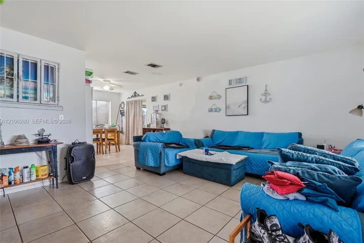 Open-concept living space featuring large-format ceramic tile flooring, neutral walls, recessed ceiling lighting, and a multi-pane decorative window accent
