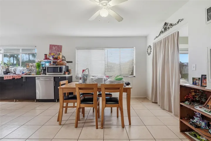 Kitchen featuring dark cabinetry, stainless steel dishwasher, tile flooring, and a ceiling fan