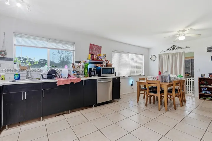 Kitchen featuring flat-panel cabinetry, stainless steel dishwasher, white subway tile backsplash, and tile flooring