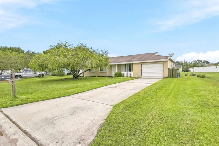 Single-story exterior featuring light-toned masonry, an attached one-car garage, and a concrete driveway situated on a spacious lawn