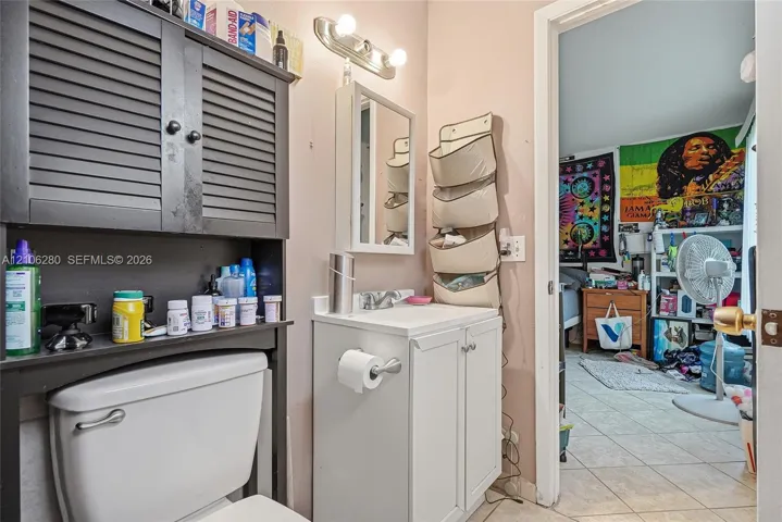 White vanity cabinet with an integrated rectangular sink, chrome faucet, wall-mounted medicine cabinet, and a multi-bulb light fixture